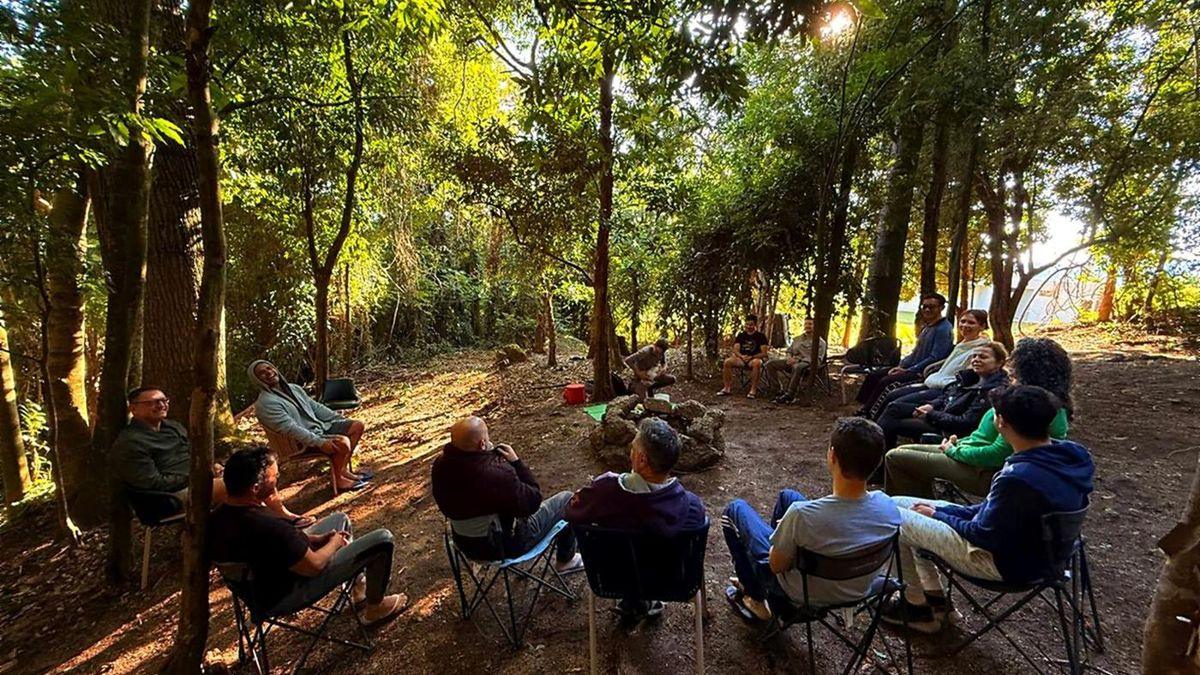 Turma em roda de conversa na mata, durante o Desafio da Montanha